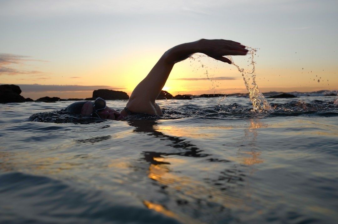 Zwemmer in open zee bij zonsondergang, met opspattend water