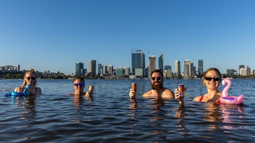 Vier mensen zwemmen met drankjes voor een moderne stads skyline