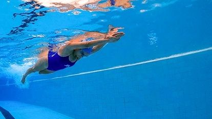 Zwemmer glijdt gestroomlijnd onder water met uitgestrekte armen