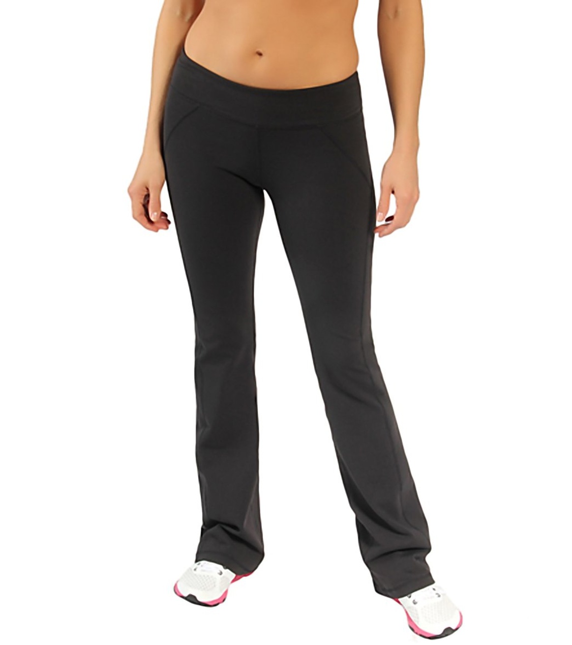 Vrouw die een zwarte sportlegging modelleert met witte sneakers tegen een witte achtergrond.